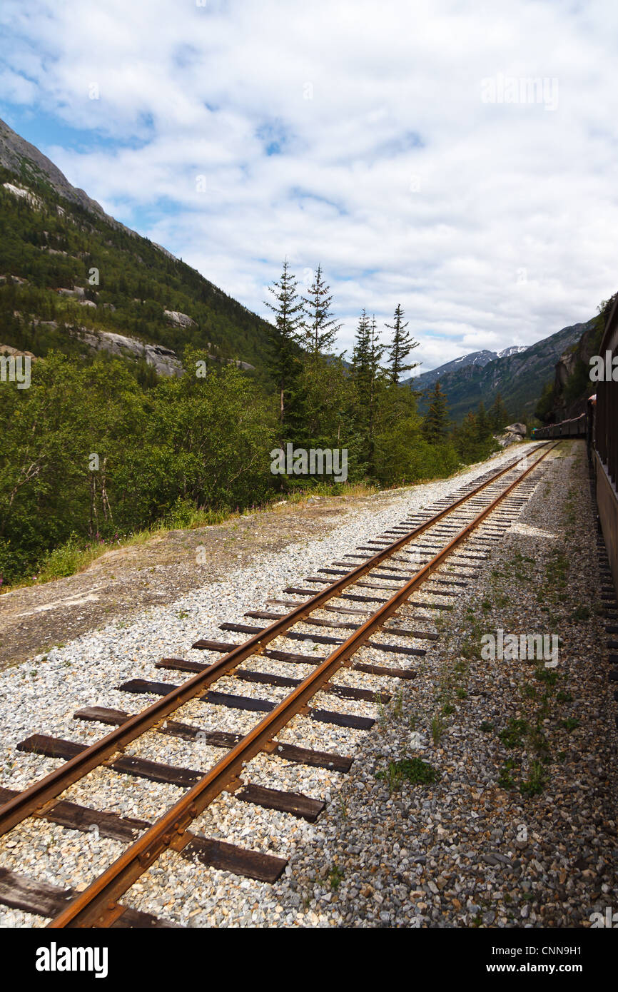 train tracks leading into the distance along side a train Stock Photo