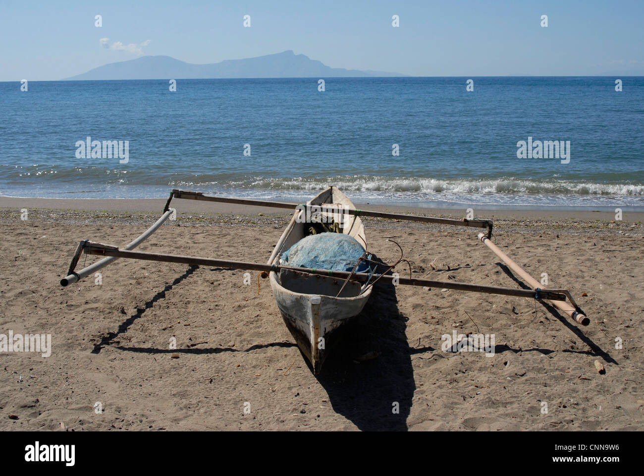 Traditional  fisherman's outrigger on the beach in Dili Timor Leste, with Atauro island on the horizon. Stock Photo