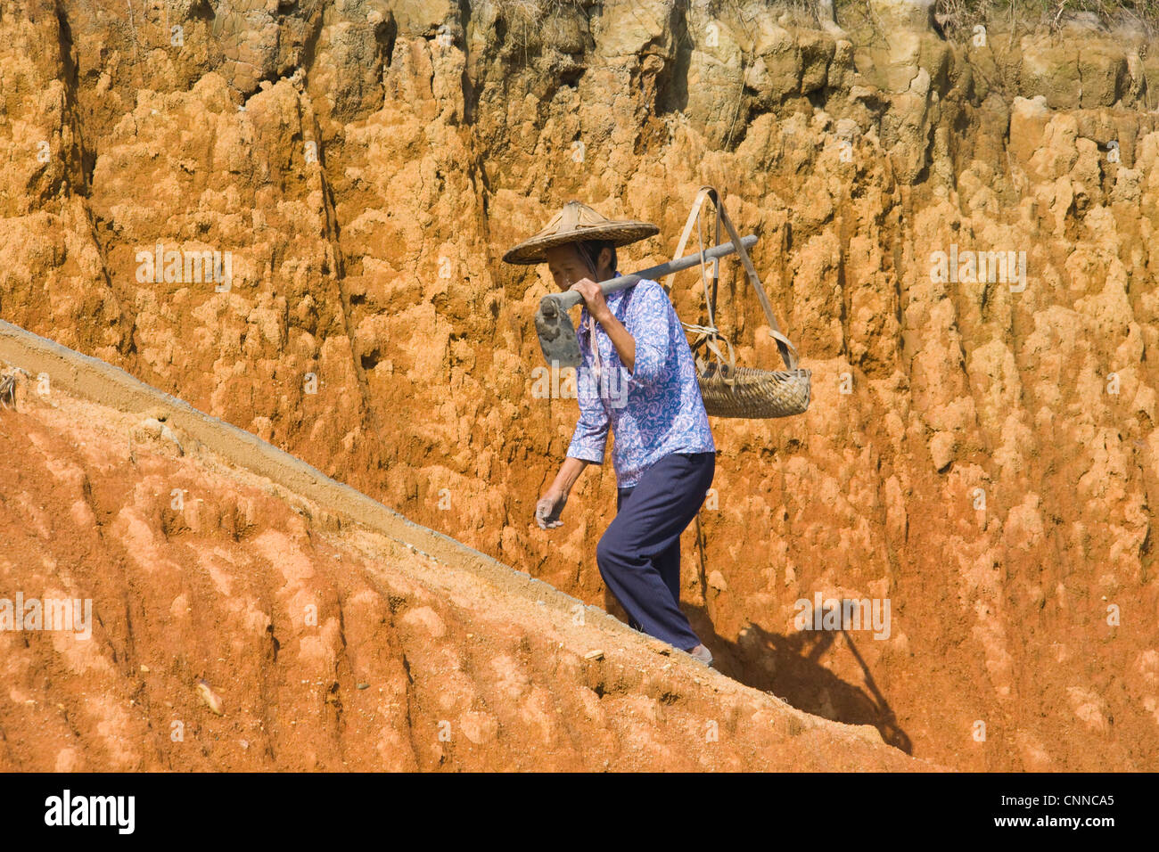 Woman carrying basket on clay hill, Yongding, Fujian, China Stock Photo