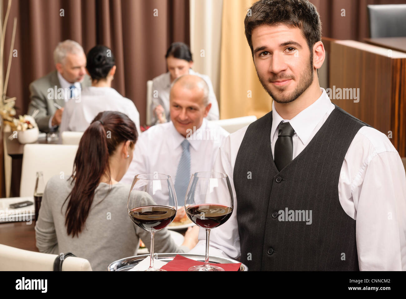 Young waiter hold red wine business lunch at professional restaurant Stock Photo