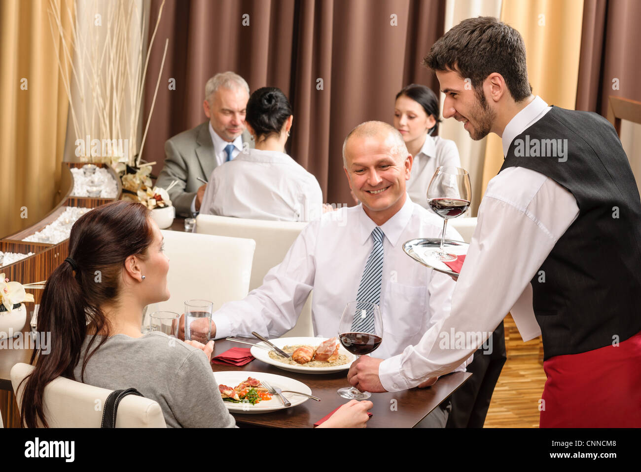 Young waiter serve wine to business people at professional restaurant
