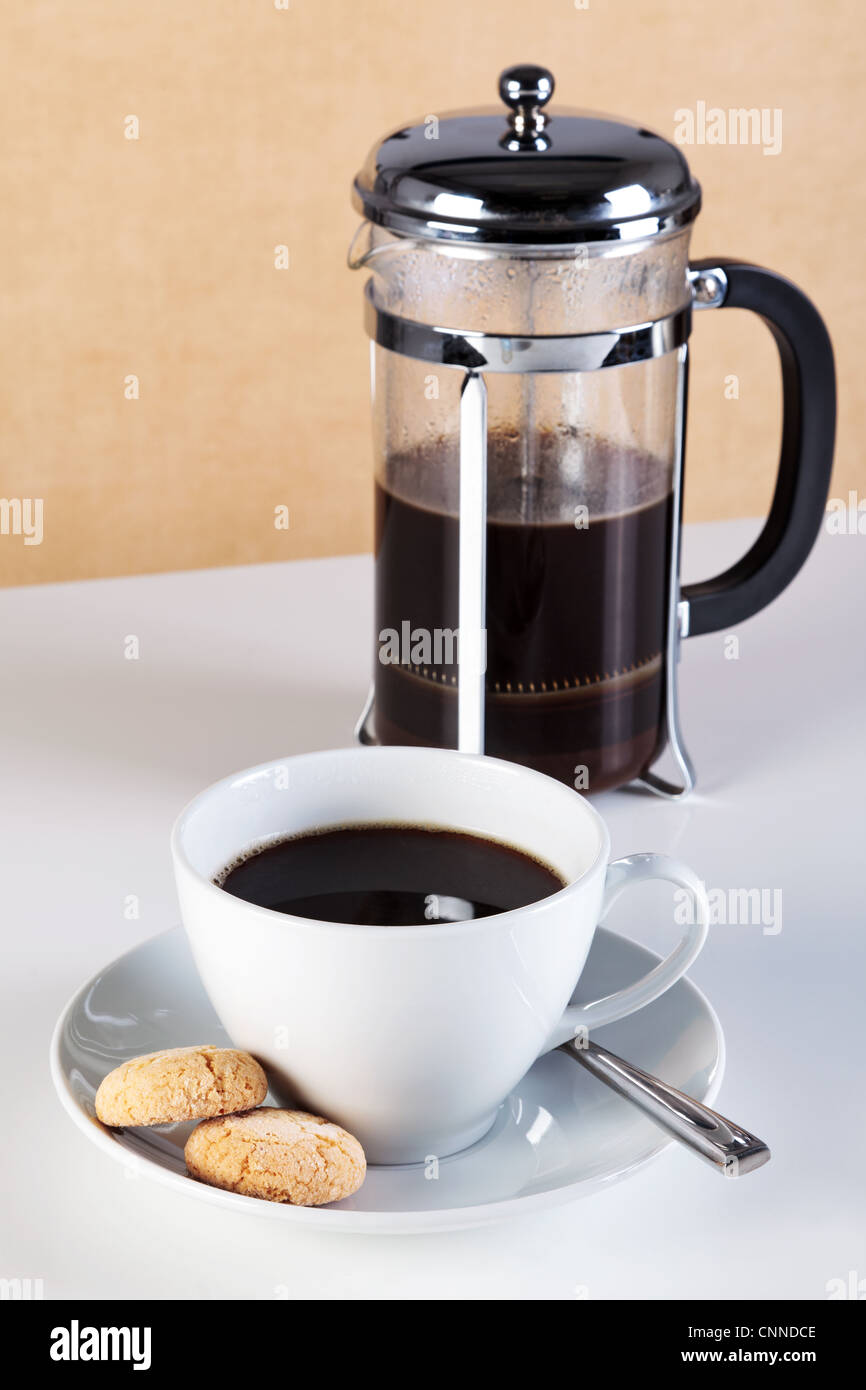 Photo of a cup of coffee with Amaretti biscuits on the saucer and a cafetiere full of freshly brewed coffee. Stock Photo