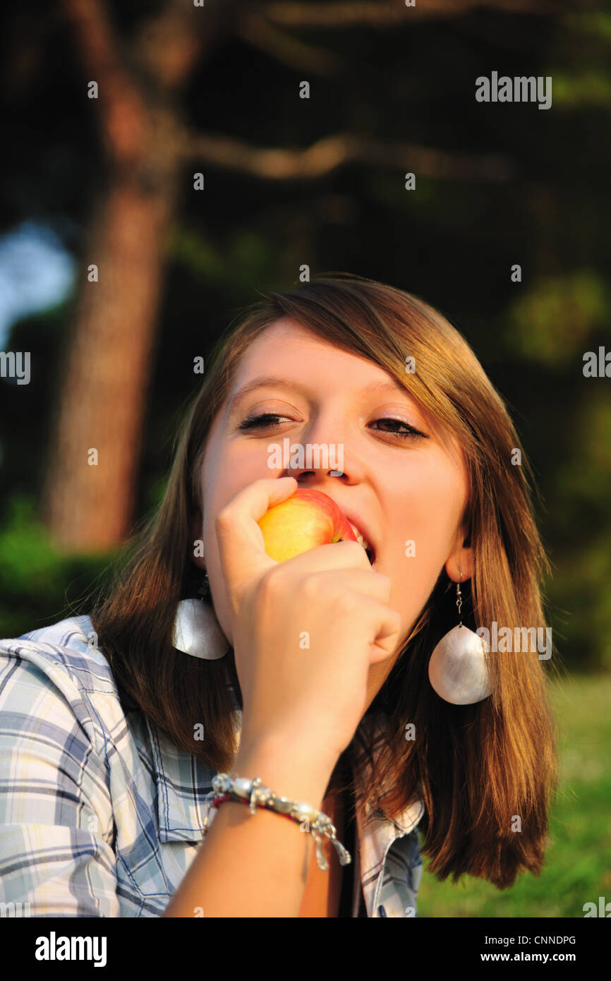 Teenage girl eating fruit in backyard Stock Photo