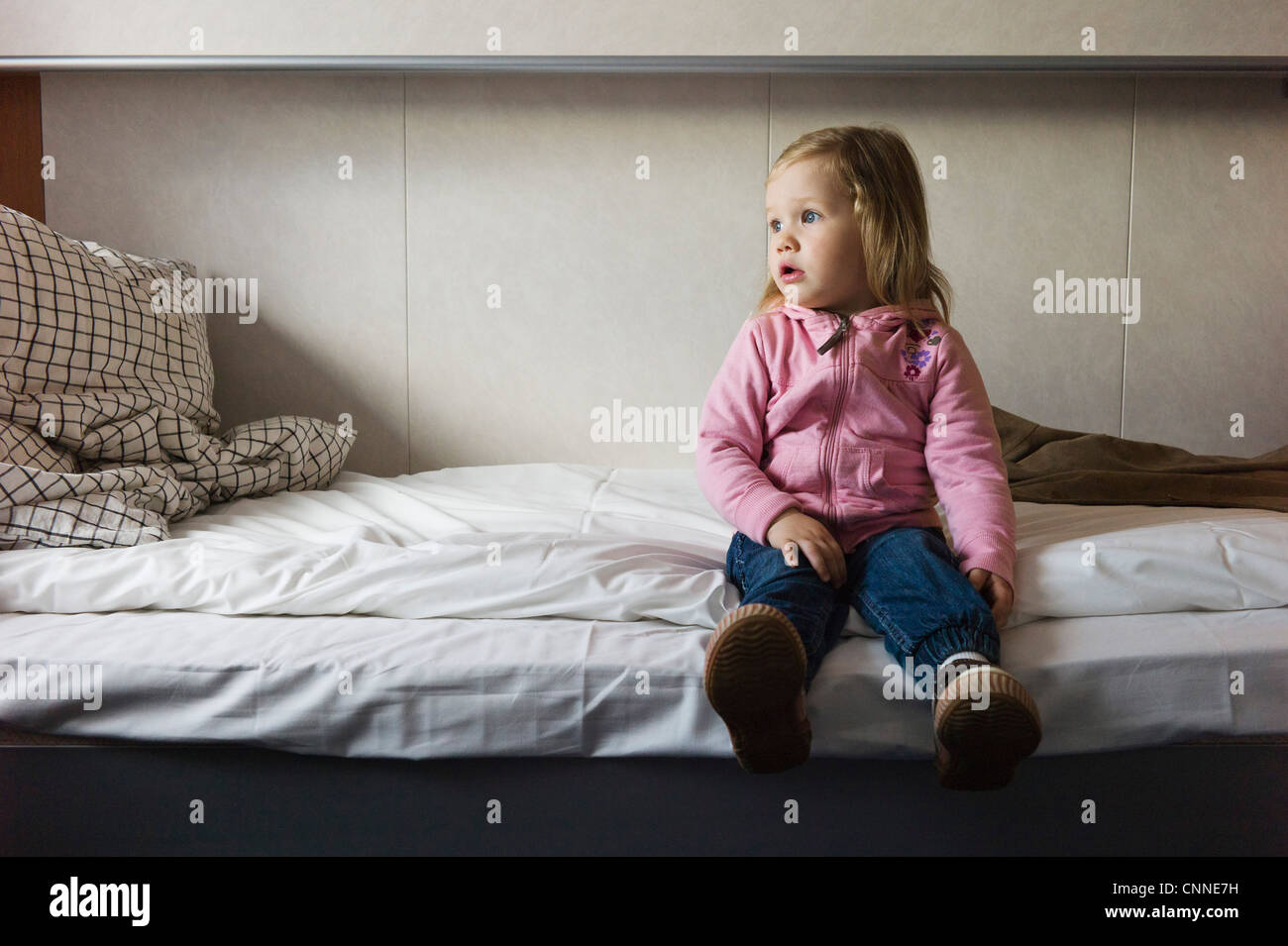 Girl Sitting on Bed, Sweden Stock Photo