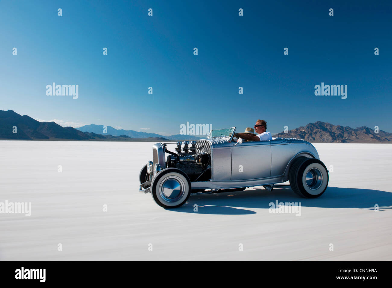 retro car driving across bonneville salt flats US blue sky white sand