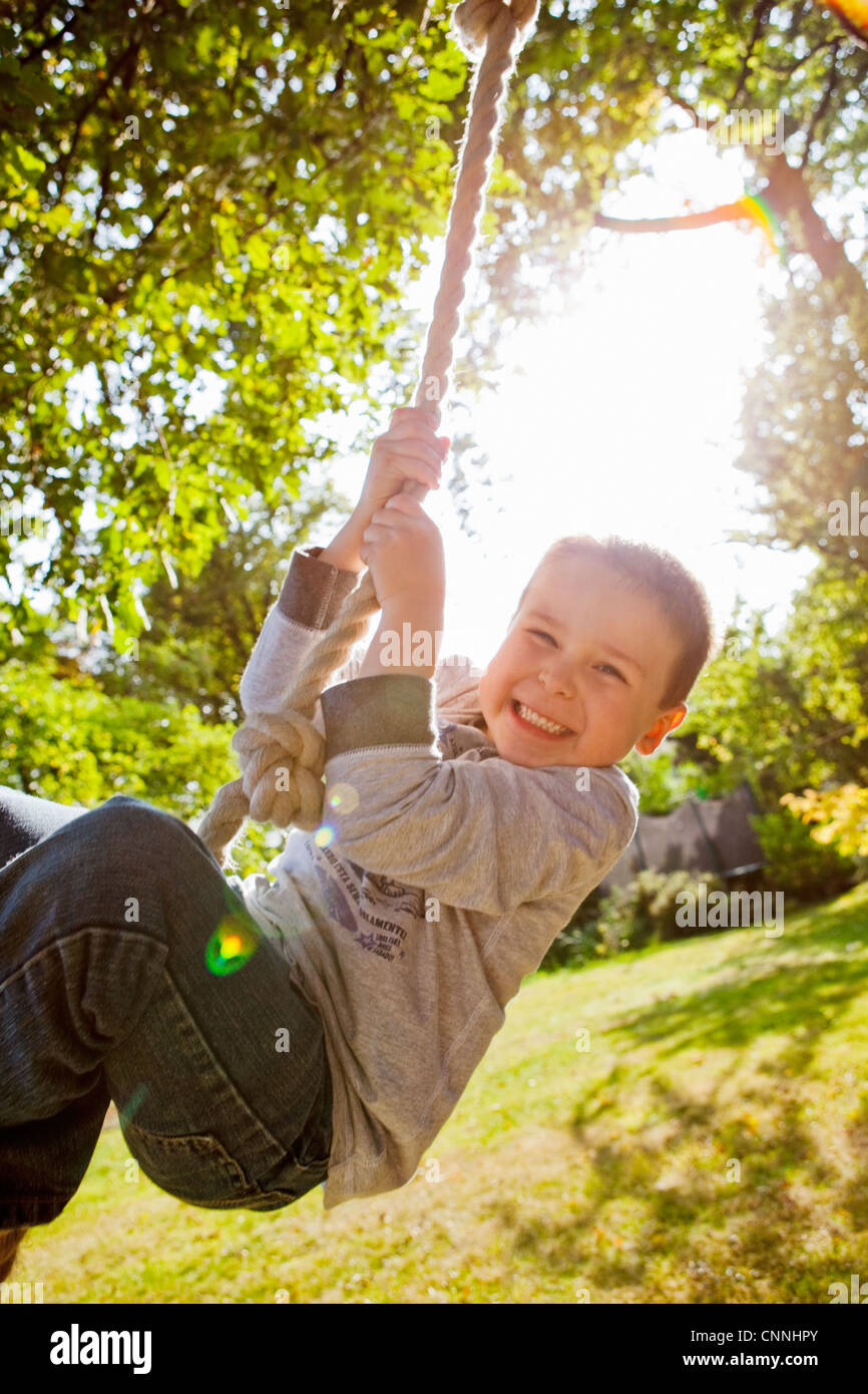 Boy playing on rope swing in backyard Stock Photo Alamy
