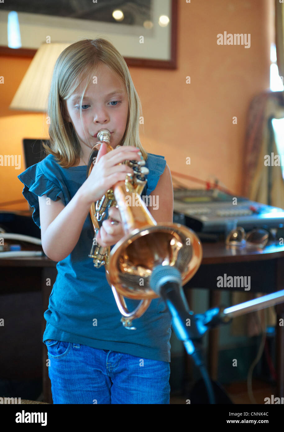 Girl playing trumpet into microphone Stock Photo