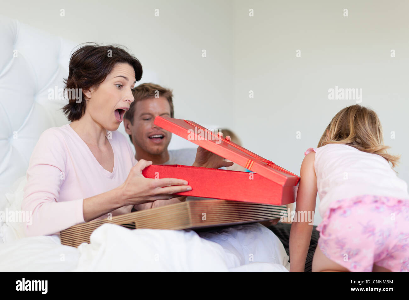 Mother opening presents in bed Stock Photo