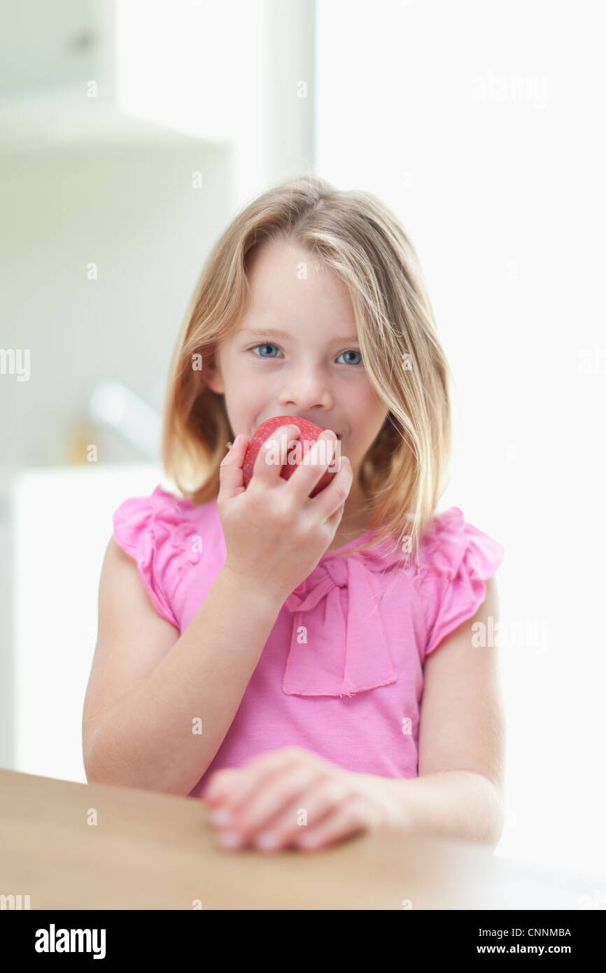 Girl eating apple in kitchen Stock Photo Alamy