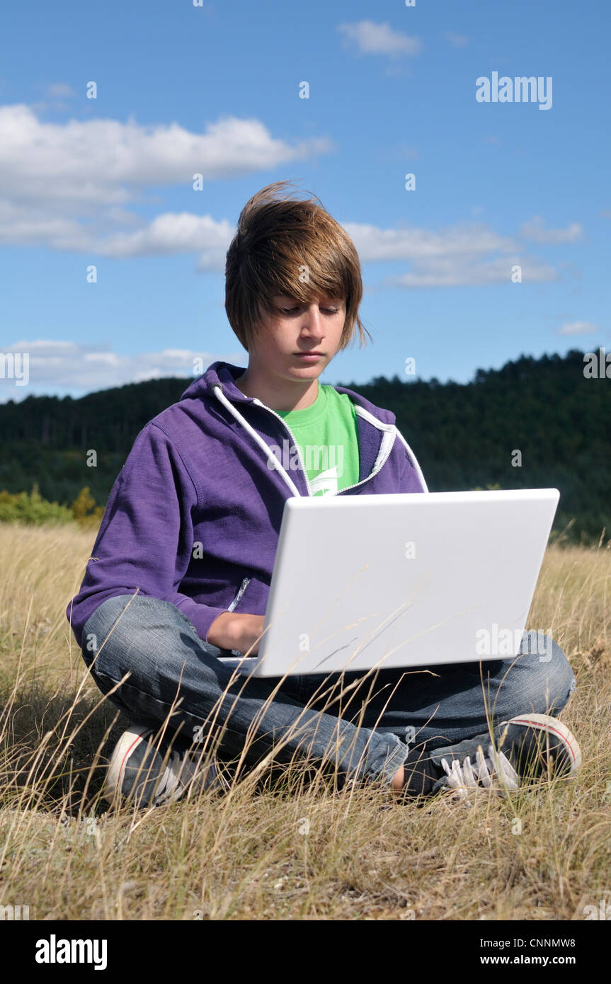 Boy Sitting in Field using Laptop Computer, Blandas, Gard, France Stock ...