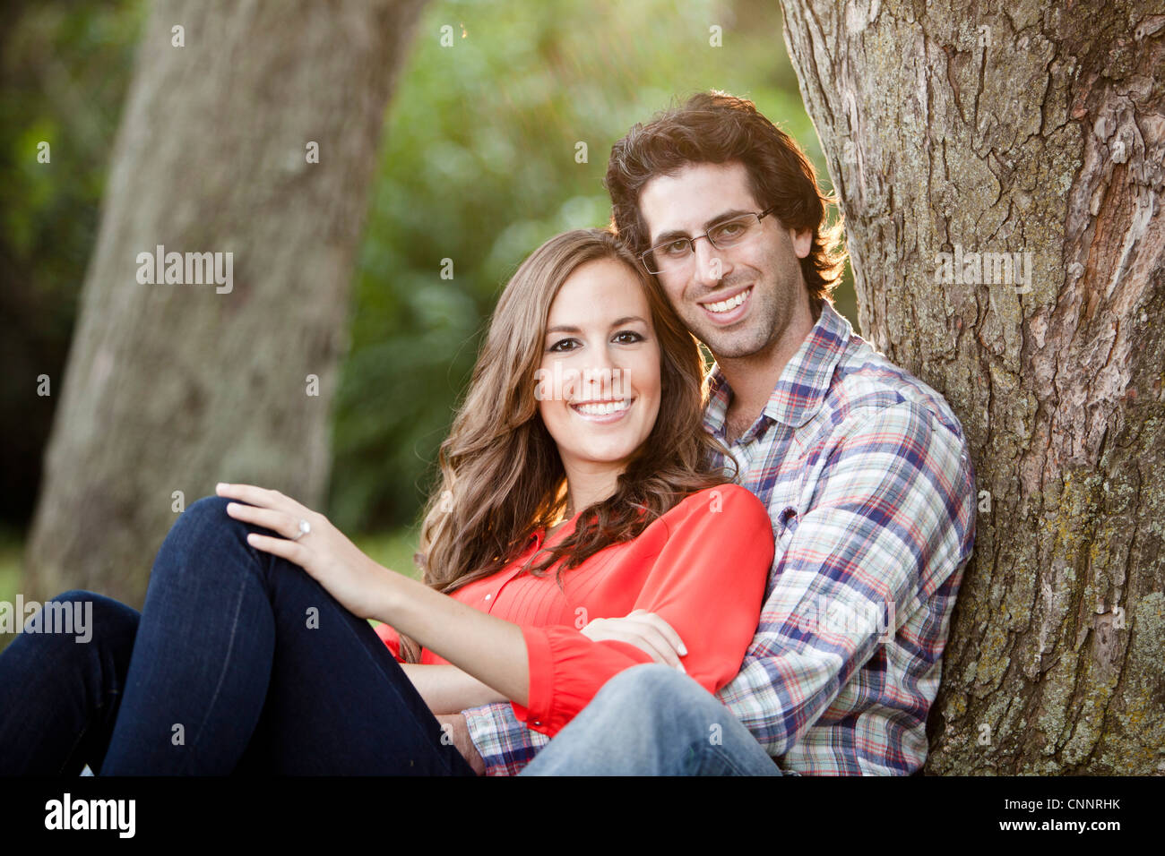 Portrait of Young Couple Sitting in Park Stock Photo - Alamy