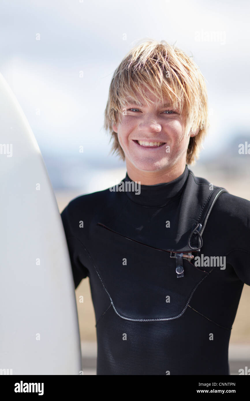 Teenage surfer holding board on beach Stock Photo
