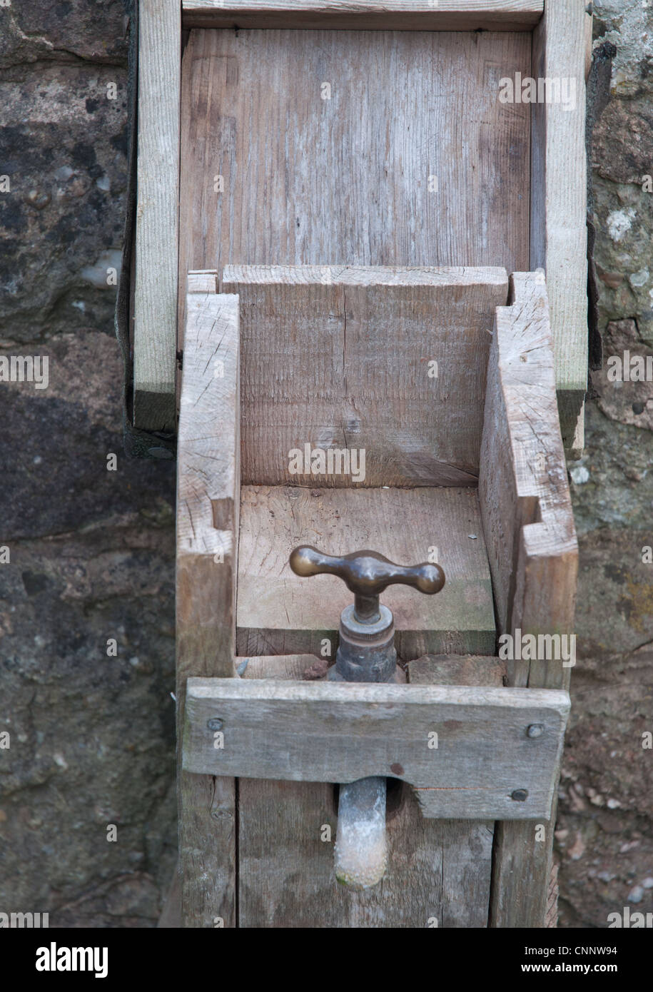 old brass external water tap providing water for churchyard contained in wooden boxing as frost protection Stock Photo