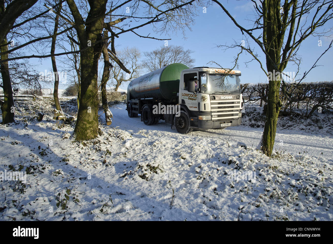 Milk tanker driving down snow covered farm track, Whitewell, Lancashire, England, november Stock Photo