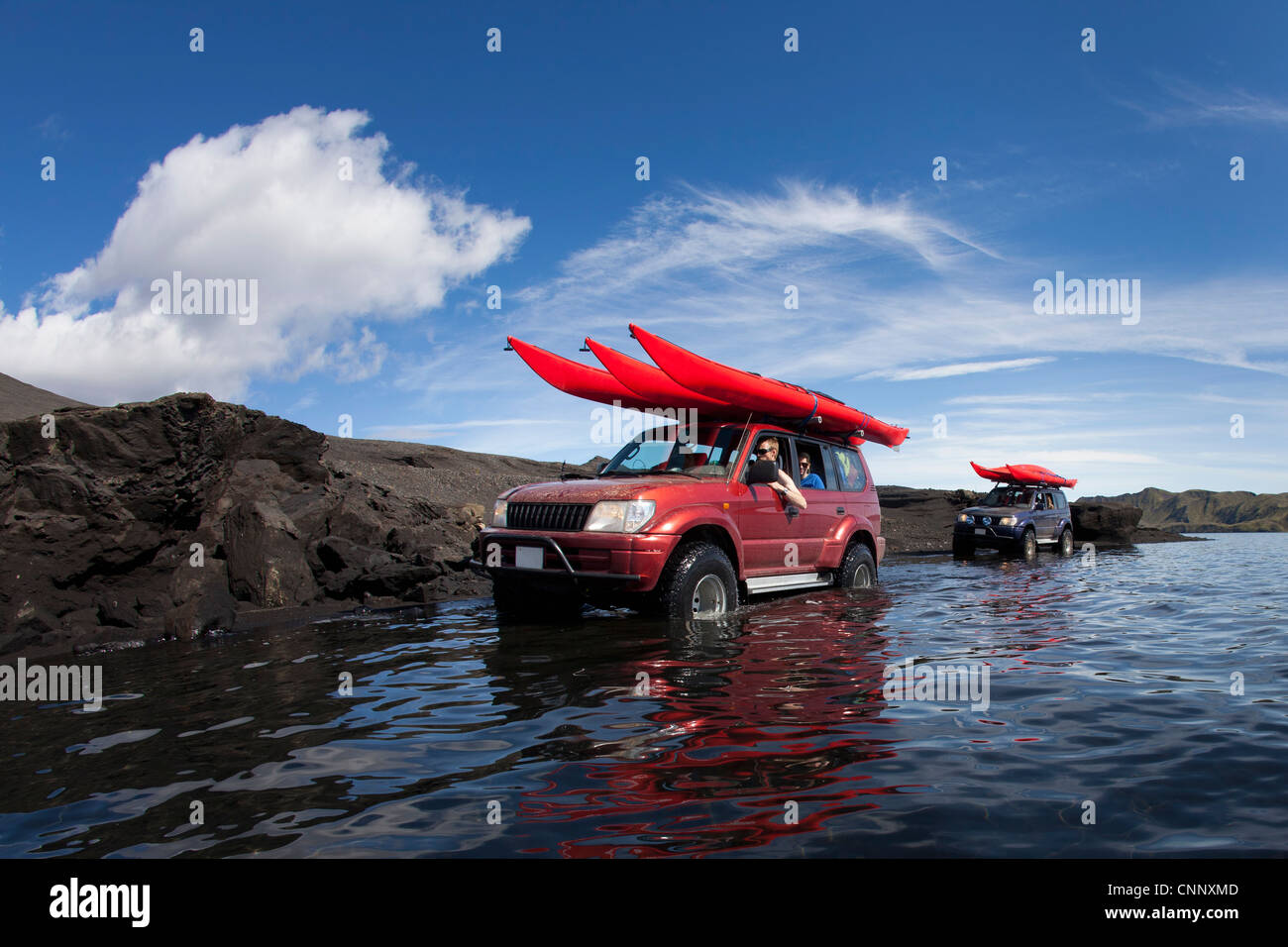 Jeeps driving through shallow lake Stock Photo