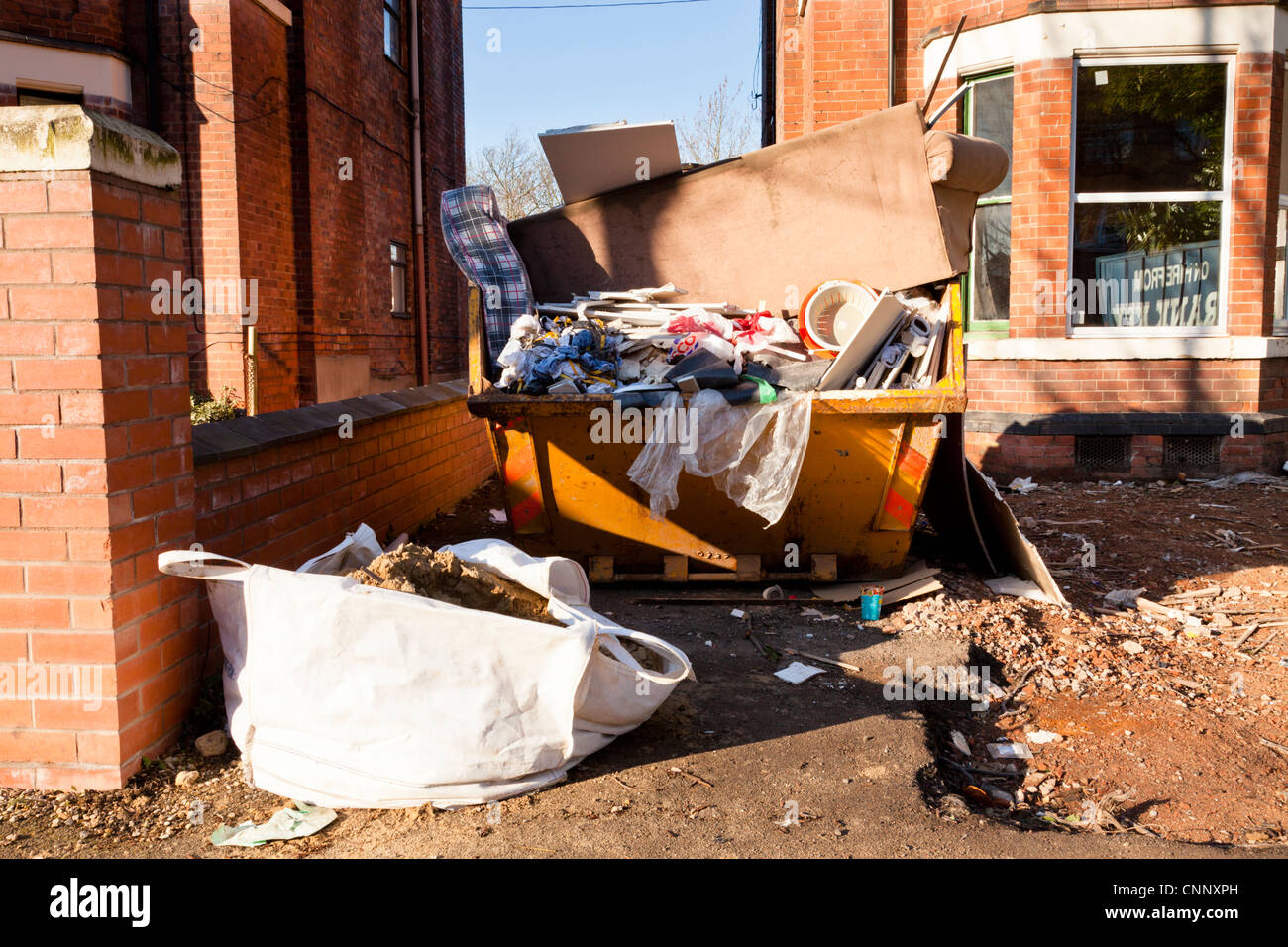 Home renovation. Full skip outside a house being renovated, England, UK Stock Photo