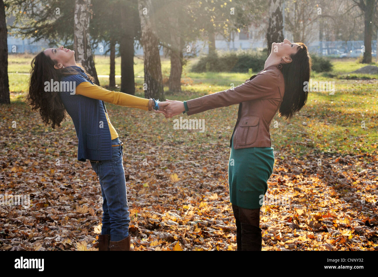 Two young women standing outdoors holding hands Stock Photo - Alamy