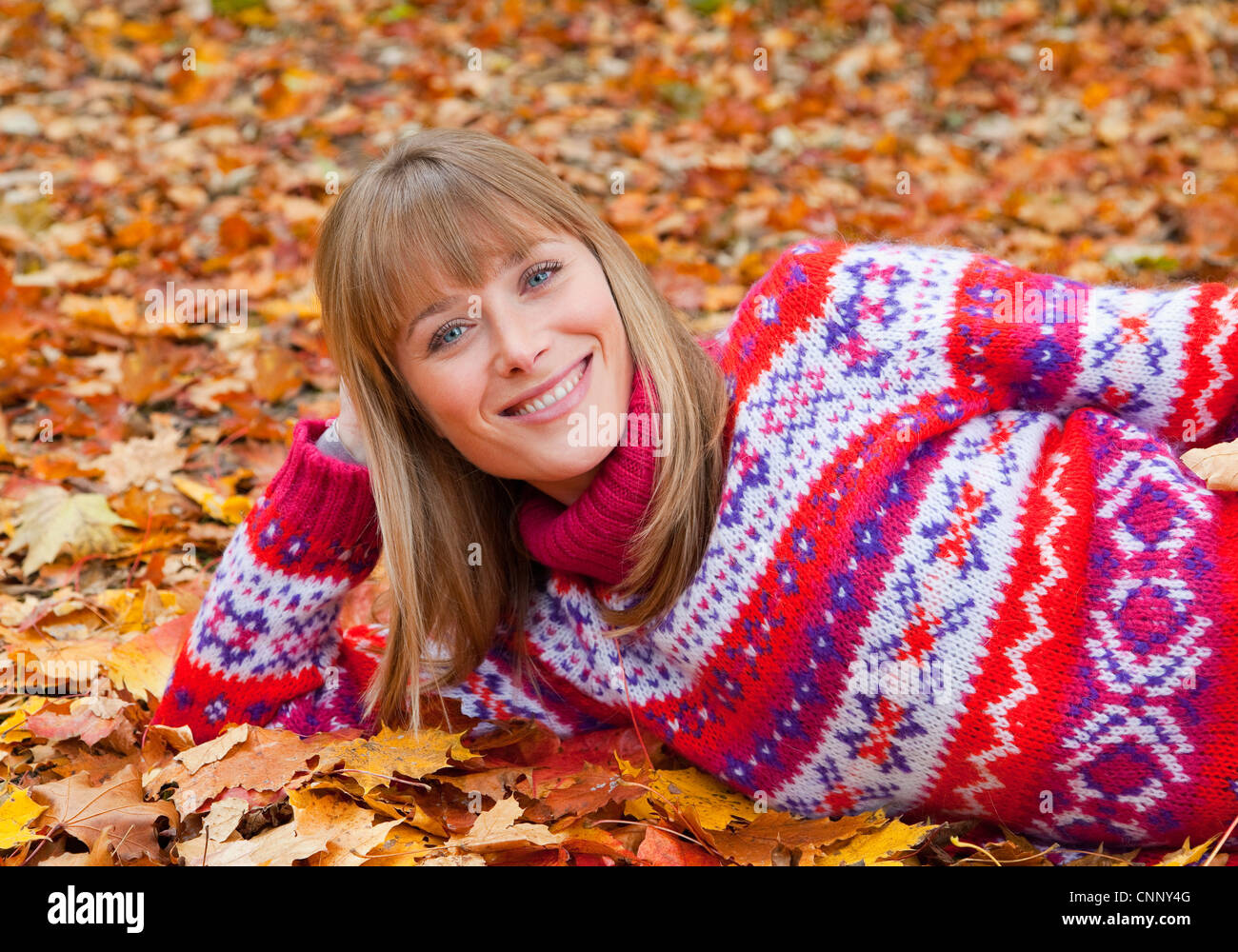 Smiling woman laying in fall leaves Stock Photo