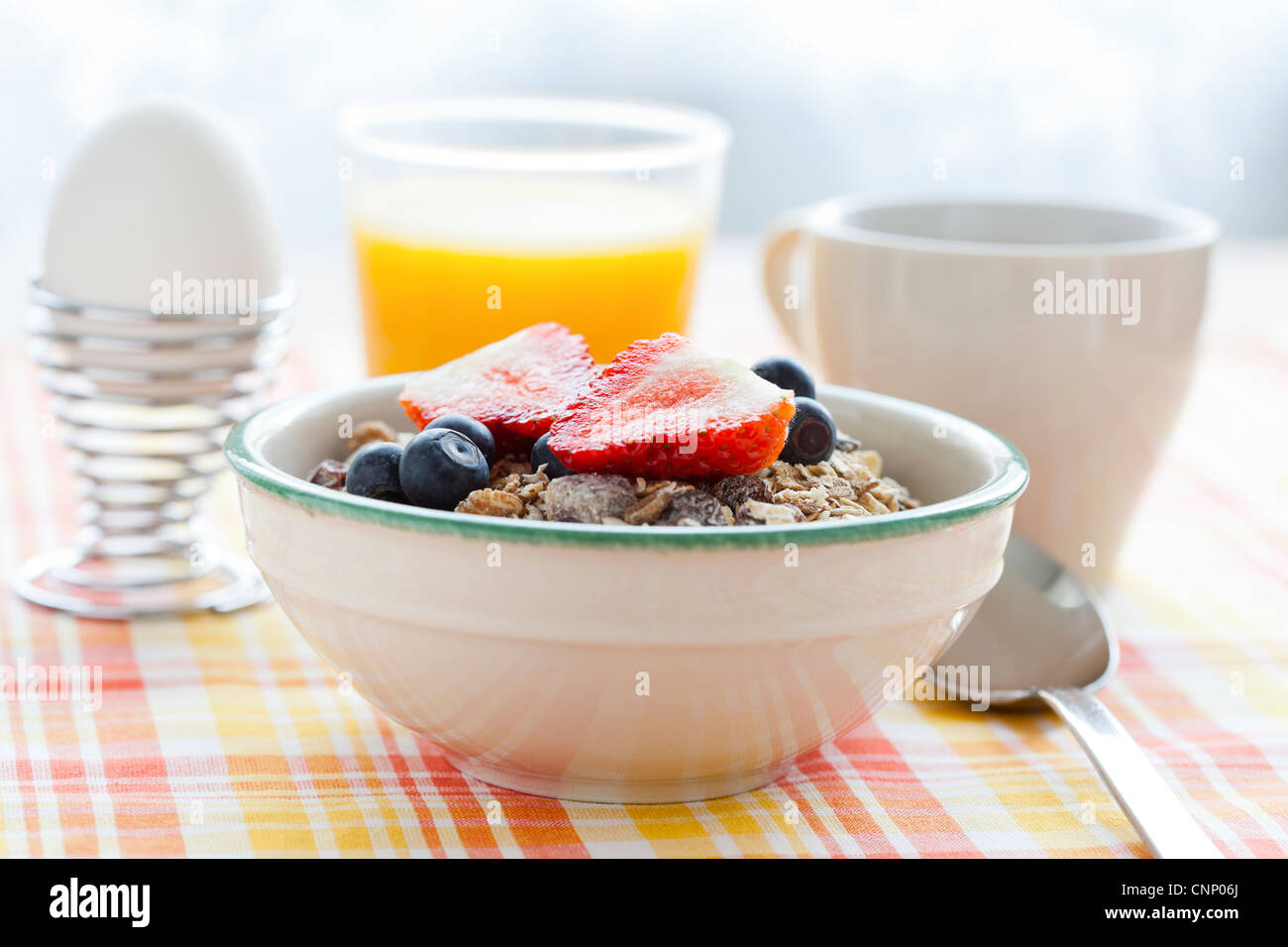 Bowl of muesli with strawberries and blueberries, boiled egg, orange juice and coffee for healthy breakfast Stock Photo