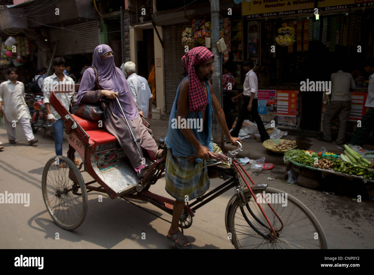 A muslim woman getting a lift on a rickshaw along busy street in Old Delhi, India Stock Photo