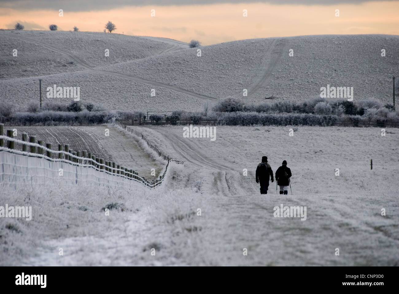 Walkers on frost snow covered footpath at sunset Ridgeway Path near