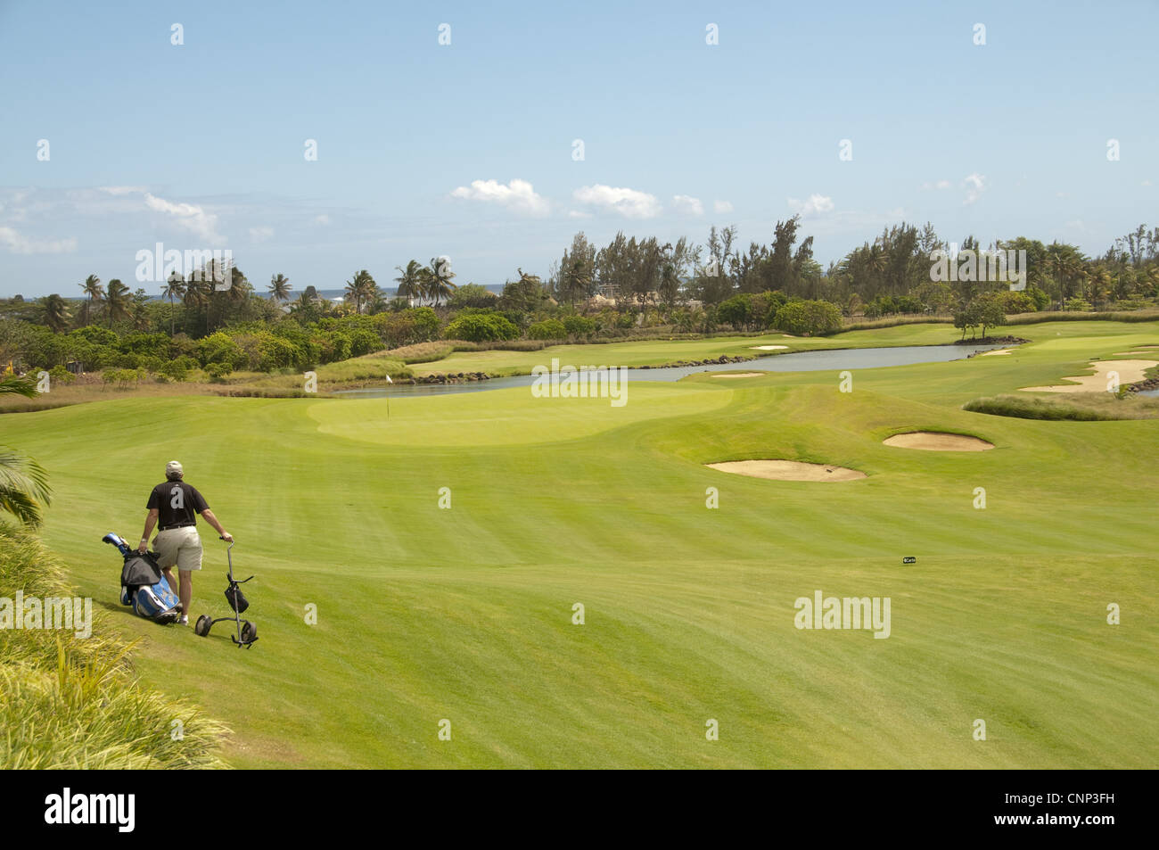 Golfer pulling golf cart across golf course, Le Telfair Hotel and Golf Course, Bel Ombre, Southwest Mauritius Stock Photo