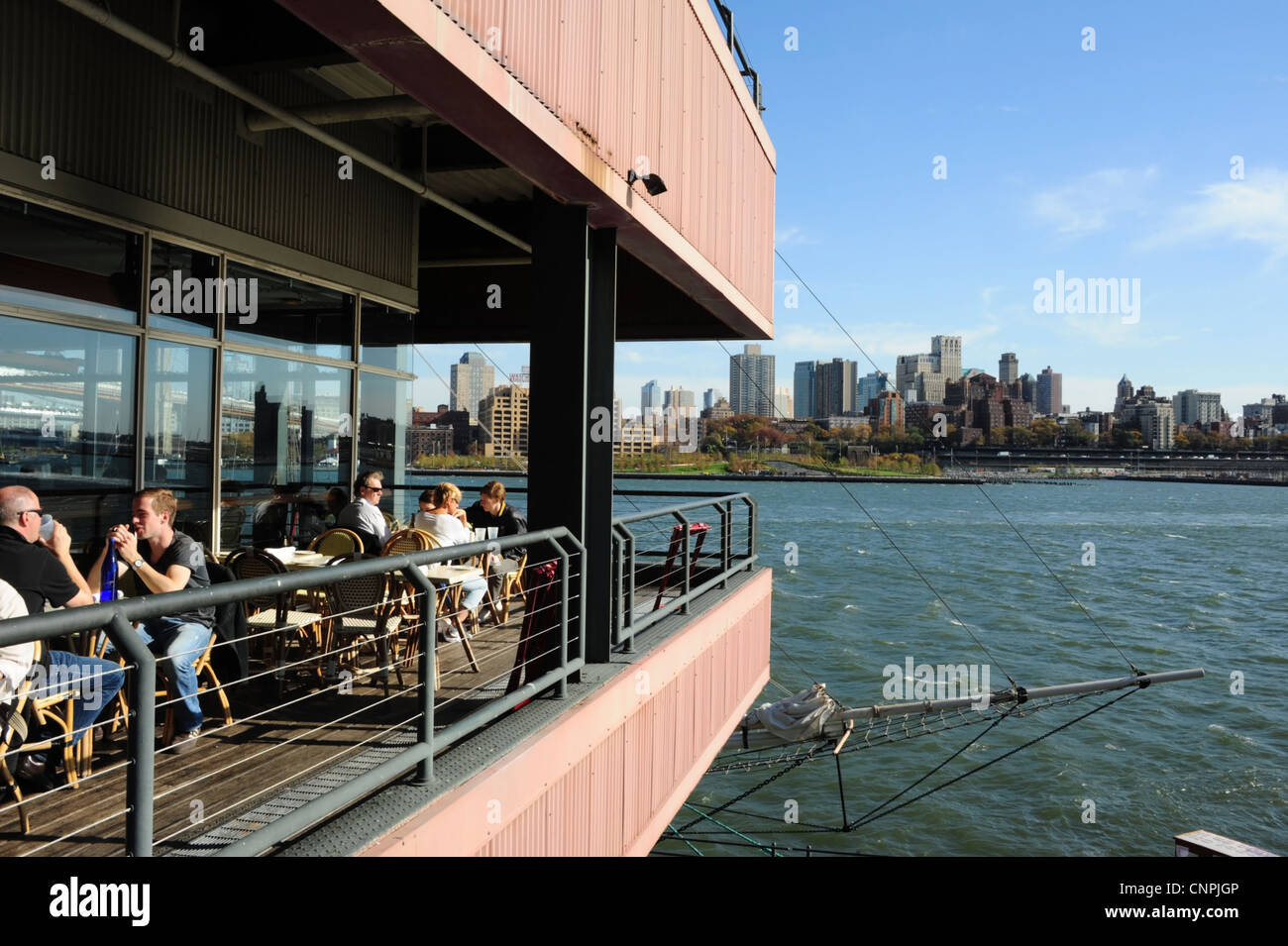 Blue sky view, to Brooklyn skyline, people sitting talking Harbour Lights Restaurant, Pier 17, South Street Seaport, New York Stock Photo