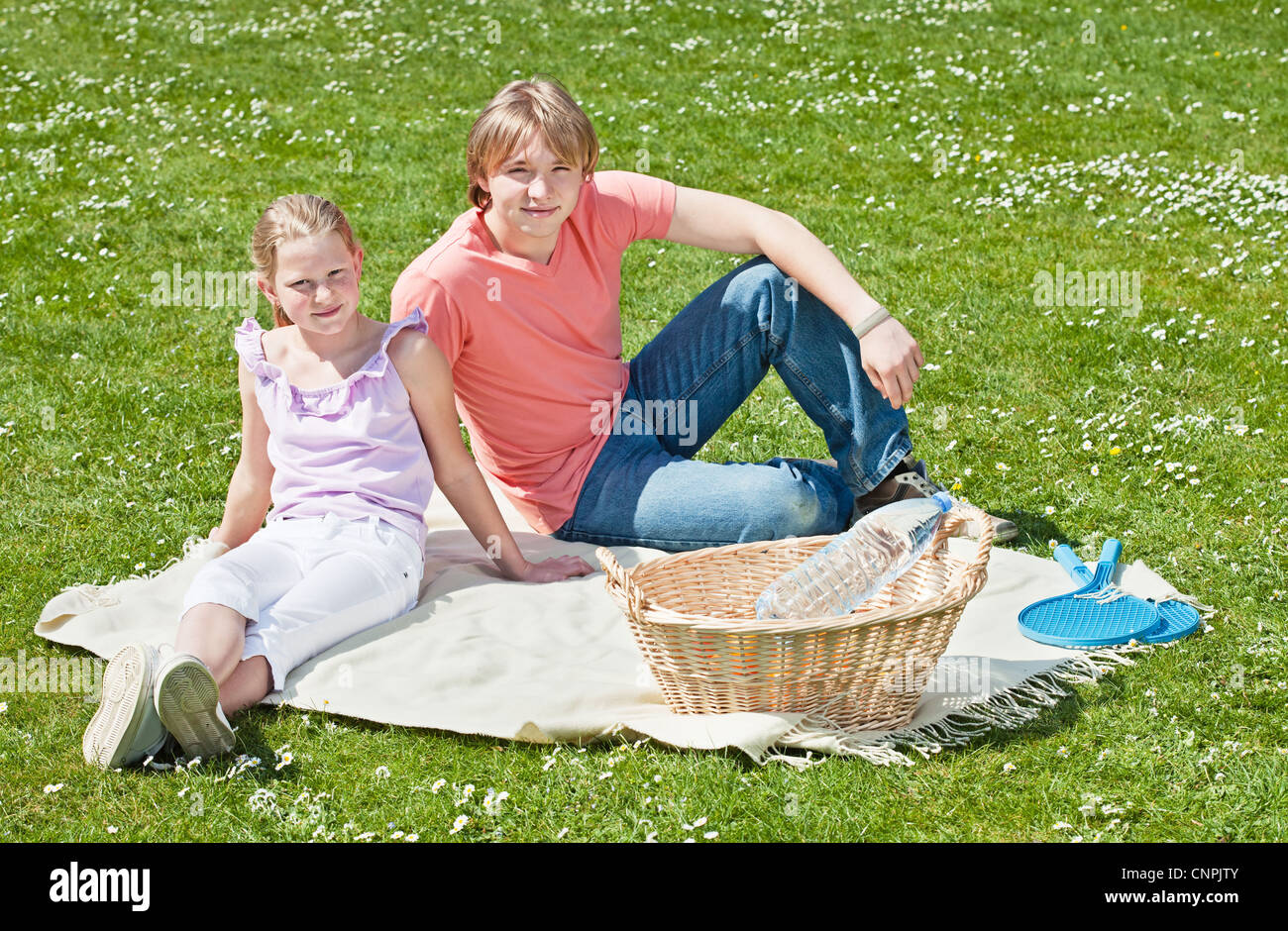 Teenager brother and sister enjoying a picnic in the park in a bright ...