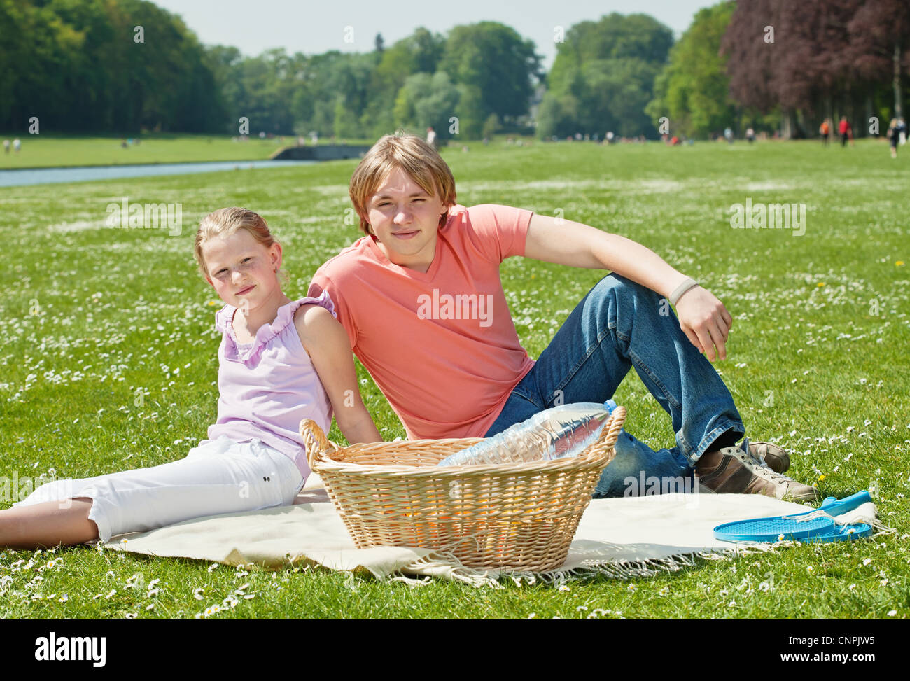 Teenager brother and sister enjoying a picnic in the park in a bright ...