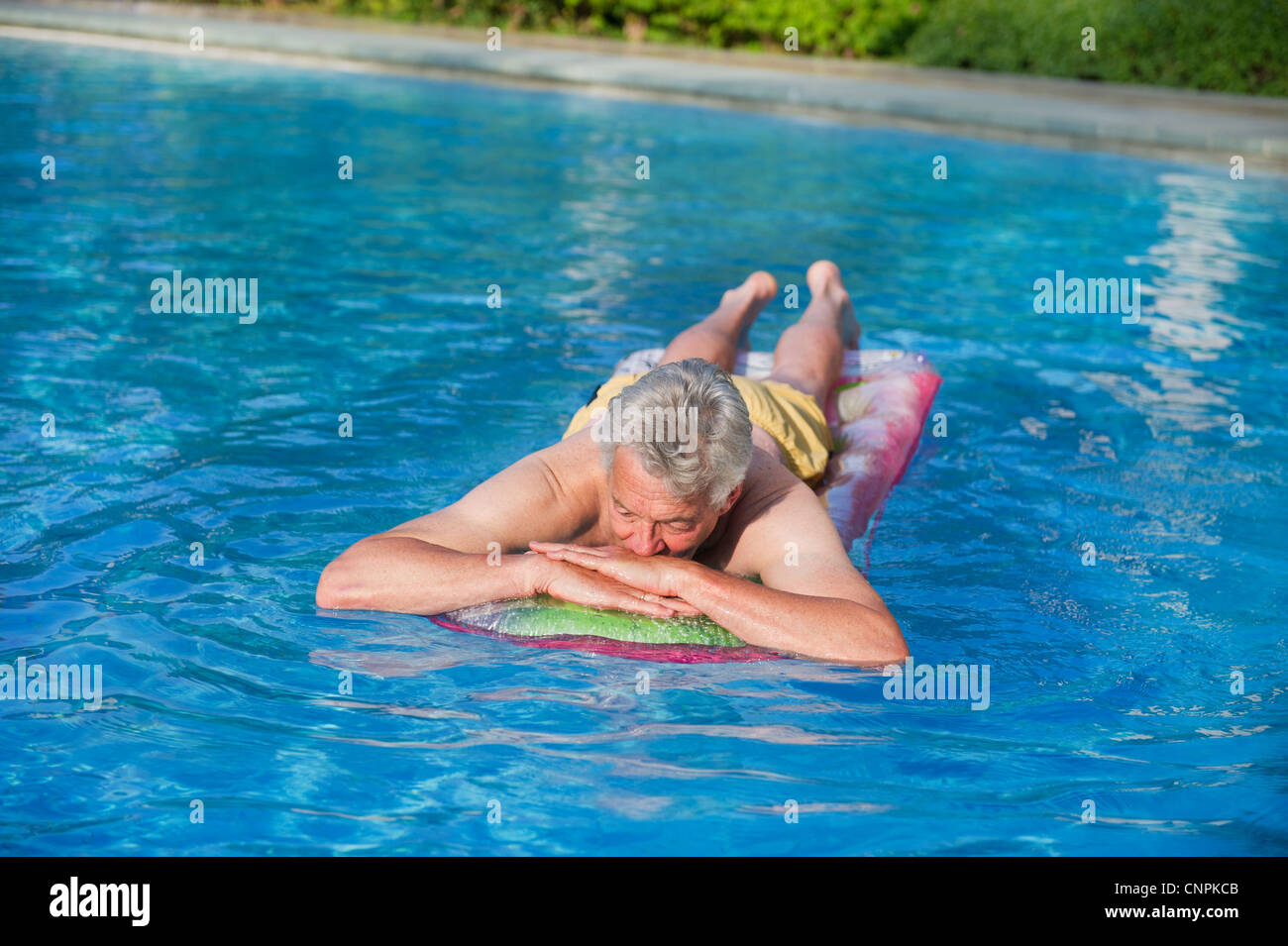 Elderly man floating on air mattress in swimming pool Stock Photo Alamy