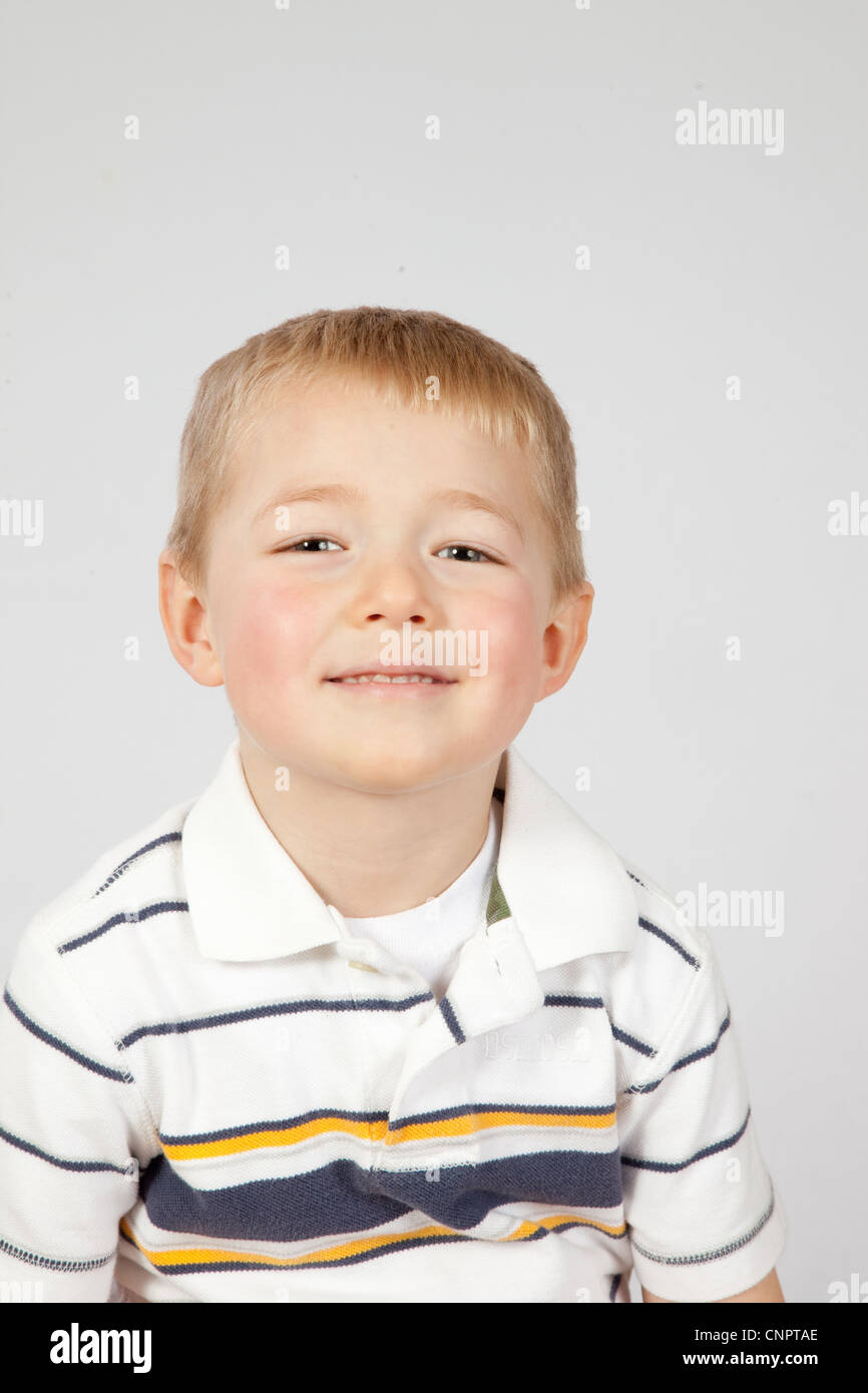 Cute blond little boy in a striped shirt, looking up with a happy grin Stock Photo