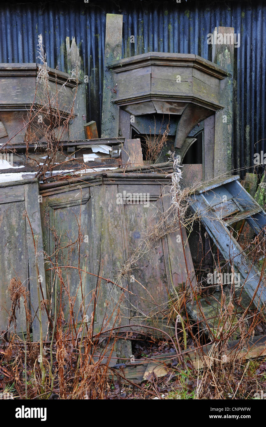 Old wooden window frame stacked outside a blue corrugated iron shed Stock Photo