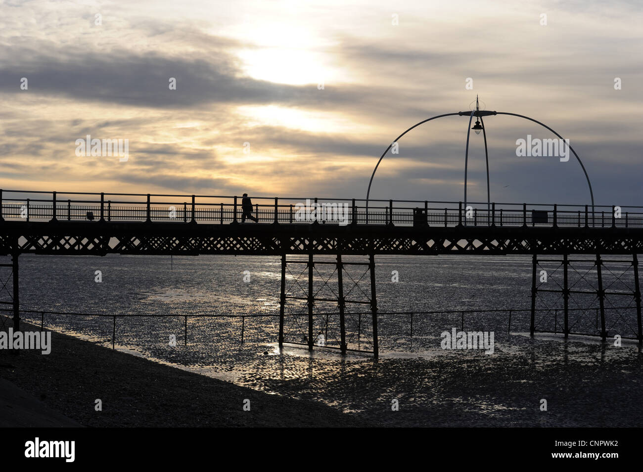 Silhouette of boy running along Southport Pier at sunset Stock Photo