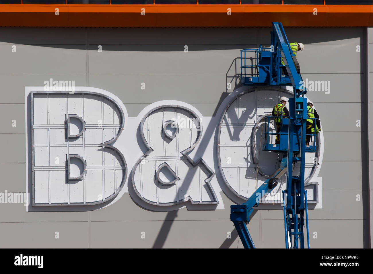 Workmen in a cherry picker erecting a B&Q sign at a new DIY store in ...