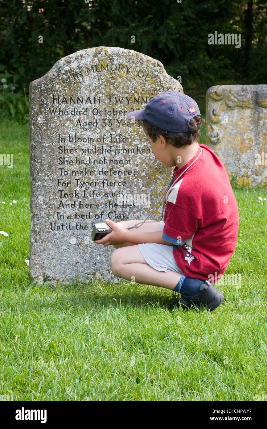 Young boy examining the grave of Hannah Twynnoy in the churchyard of Malmesbury Abbey Stock Photo
