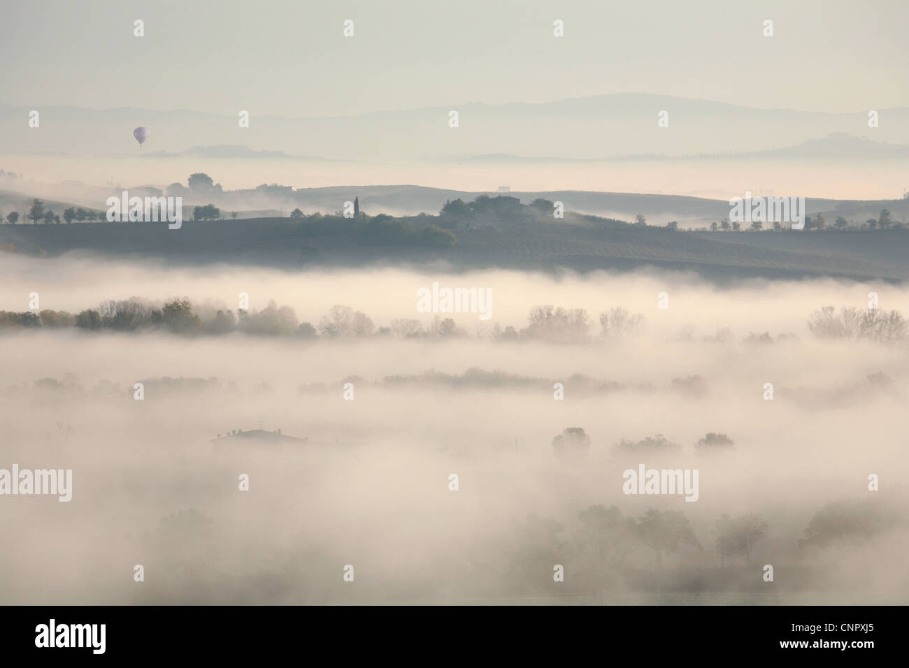 Hot air balloon over early morning dawn mist near Siena,  Tuscany, Italy Stock Photo