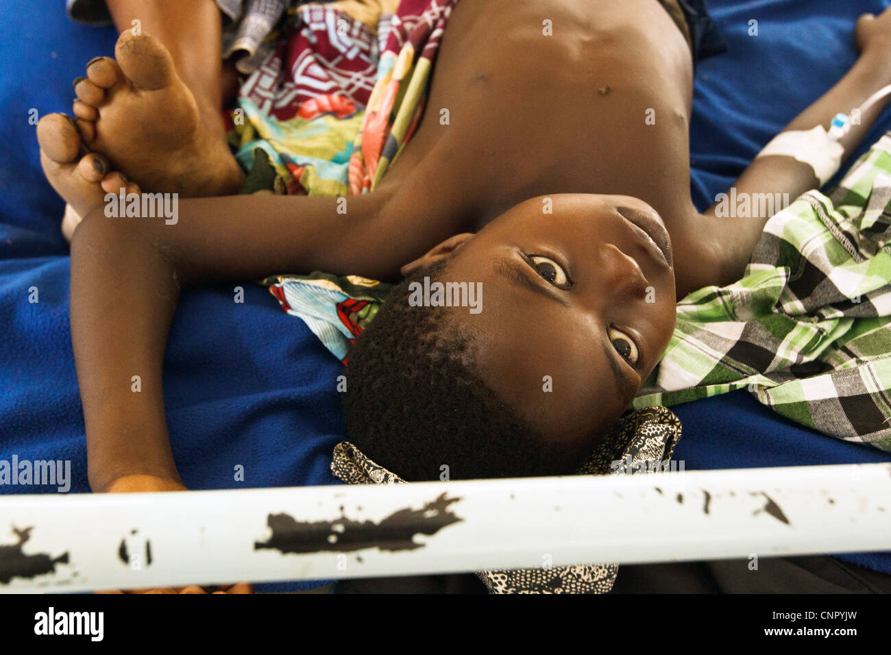 A boy who suffers from malaria lies on a bed in a clinic run by MSF next to the Tabacongo health center, in Tabacongo Stock Photo