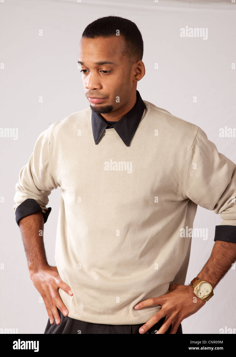 Thoughtful young black man, wearing sweater and looking all pensive and sad with his hands on his hips Stock Photo