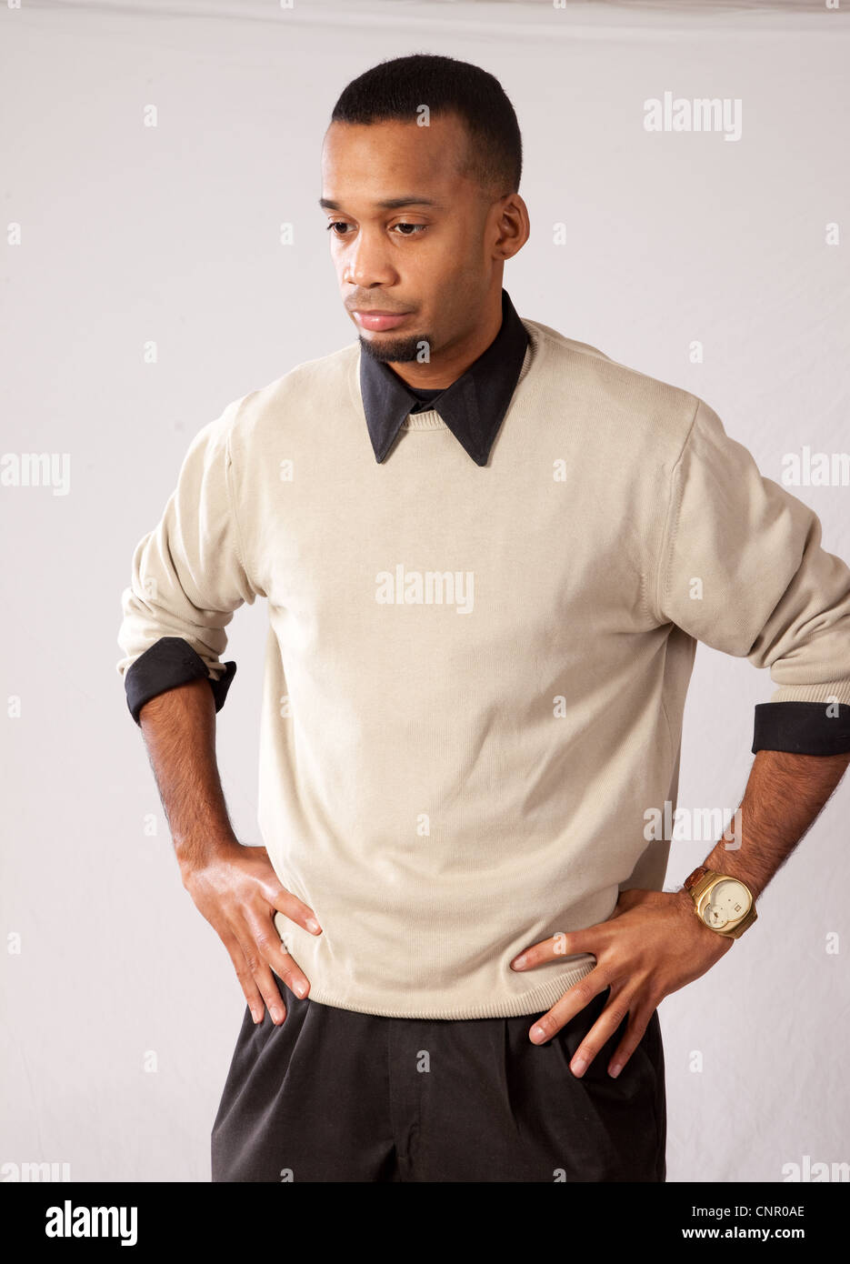 Thoughtful young black man, wearing sweater and looking all pensive and sad with his hands on his hips Stock Photo
