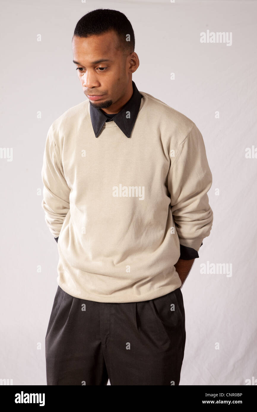 Thoughtful young black man, wearing sweater and looking all pensive and sad with his hands behind his back Stock Photo