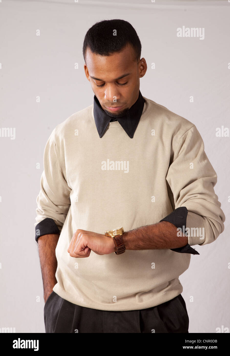Thoughtful young black man, wearing sweater and looking all pensive looking at his watch Stock Photo