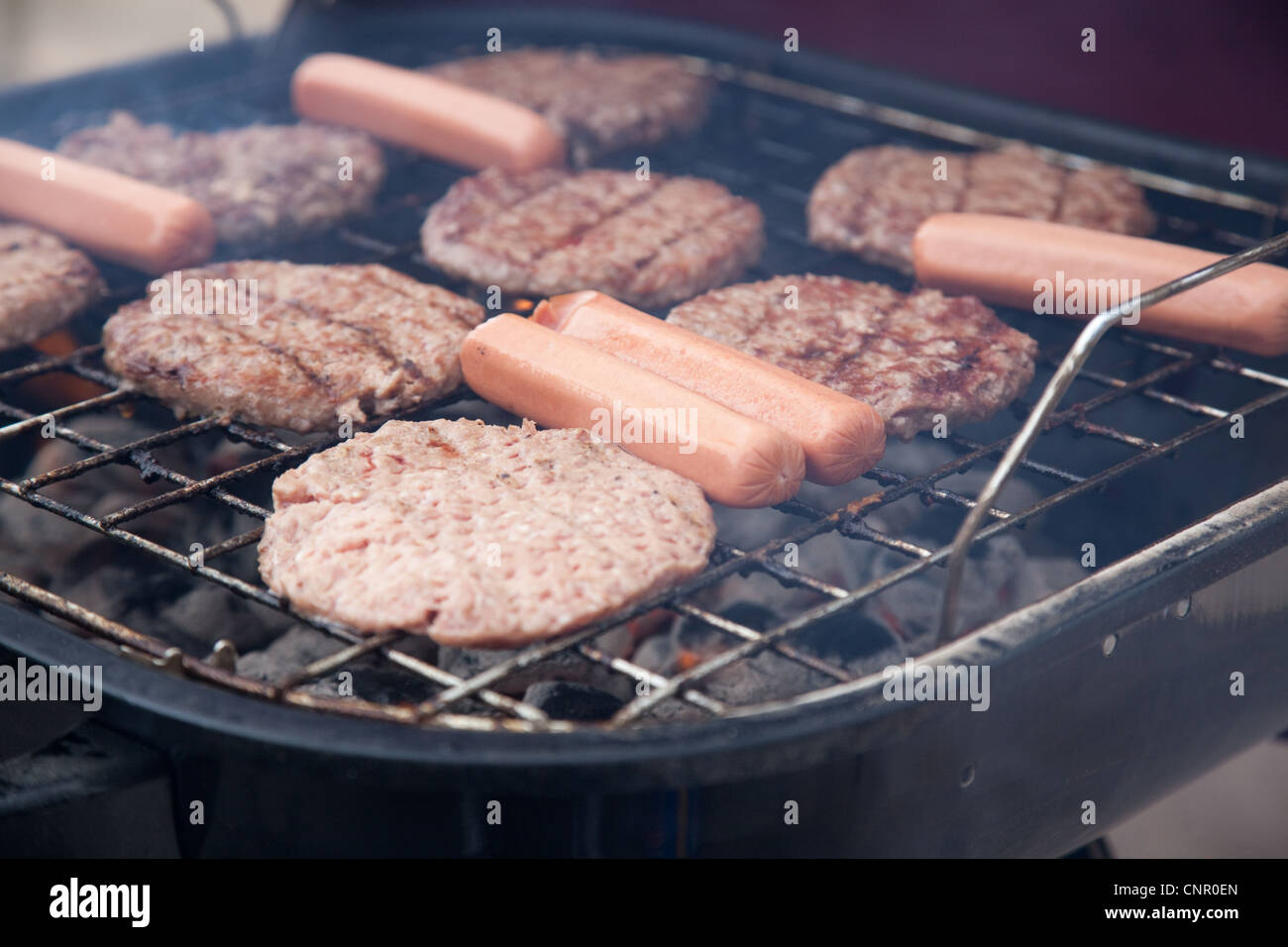 Hot dogs and hamburgers on the grill as they cook ouotside Stock Photo