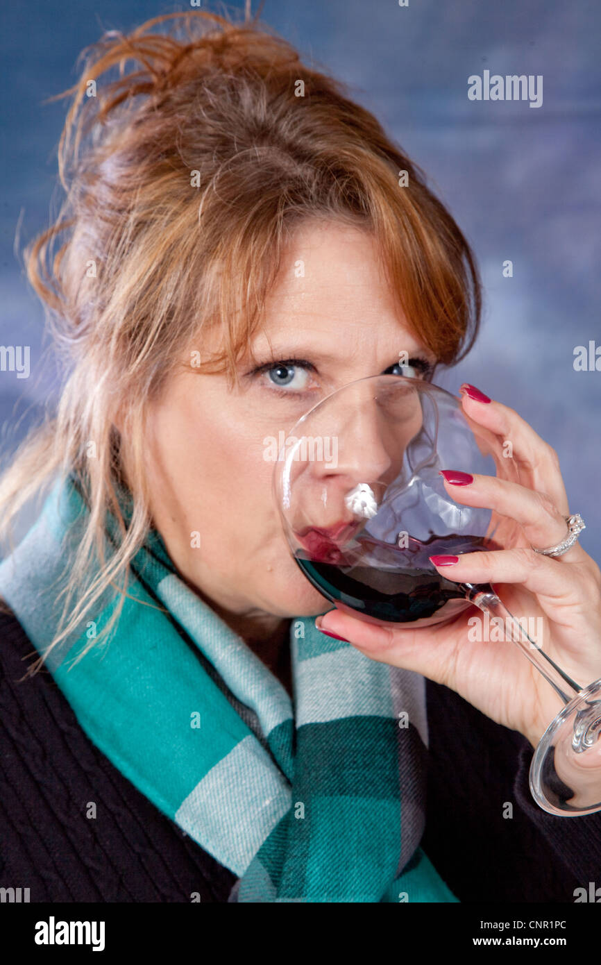 Lovely mature woman drinking glass of red wine and looking at the ...
