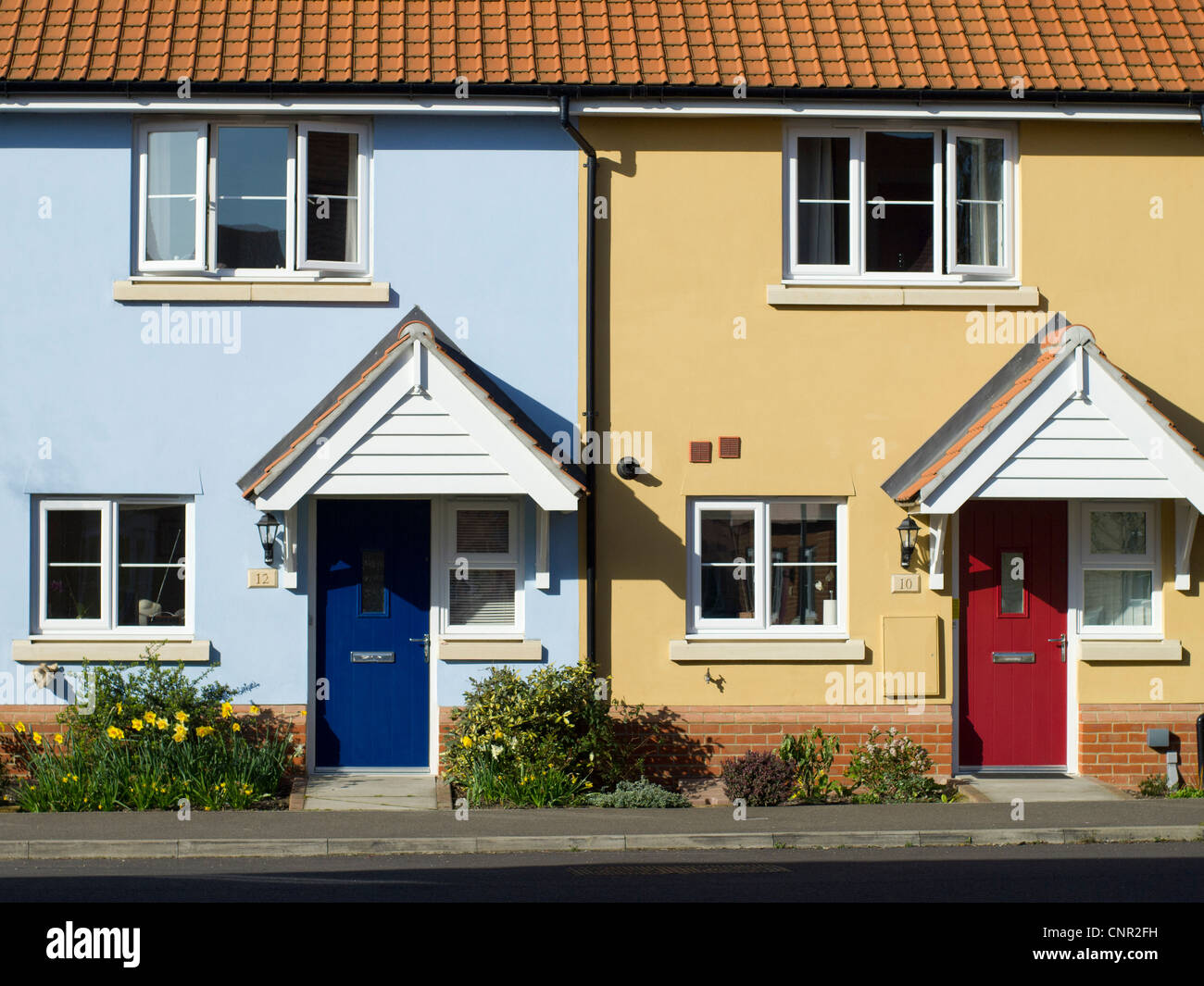 The front of two small terraced houses, painted blue and pink, with