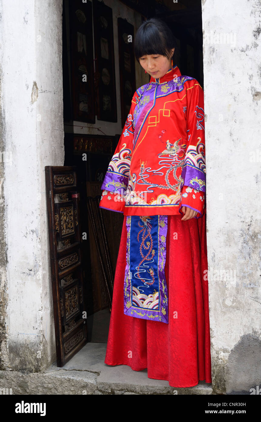 Young bride wearing her red wedding dress in the doorway of a Hongcun village building Peoples Republic of China Stock Photo