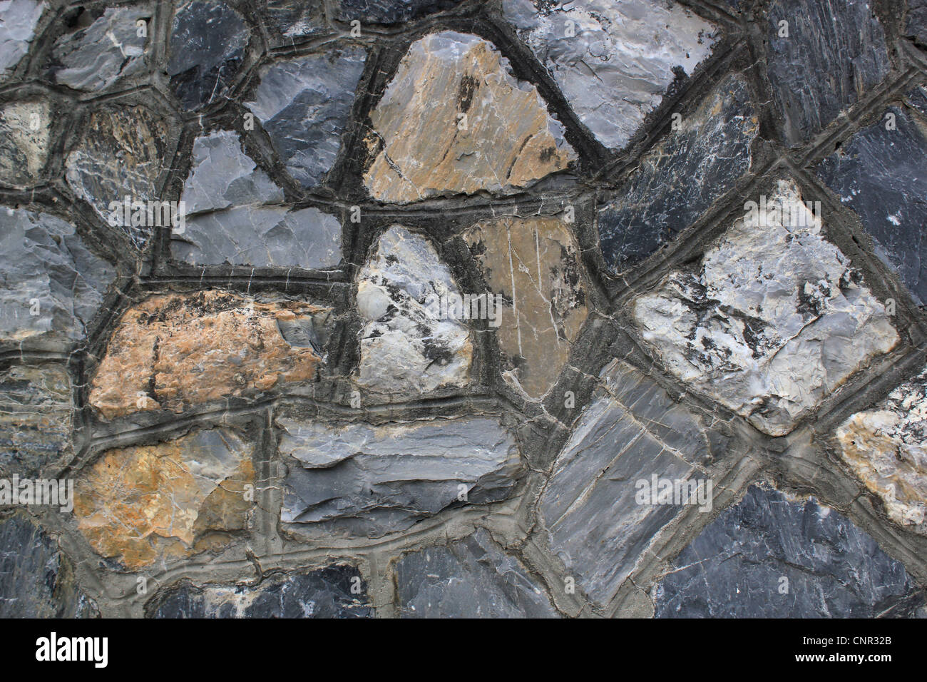 Close up of a grey wall made of different size rocks in the mountain ...