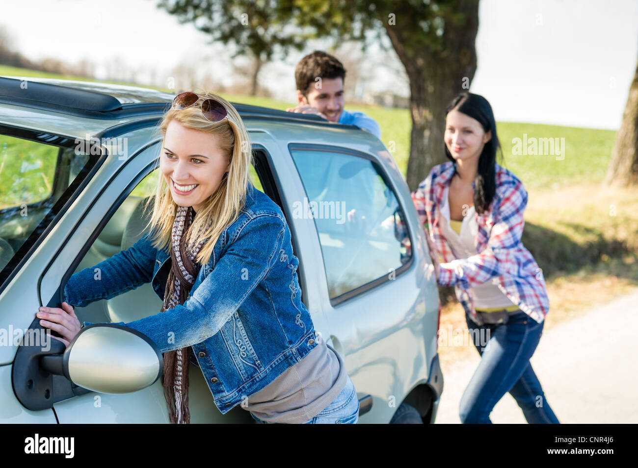 Vehicle breakdown young people pushing car down the road Stock Photo