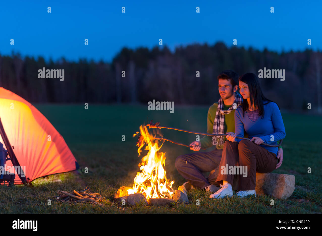 Camping night couple cook by campfire backpack in romantic countryside