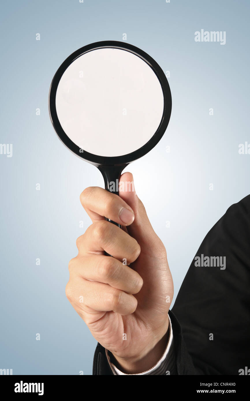 Magnifying glass in hand on blue background (path in side) Stock Photo