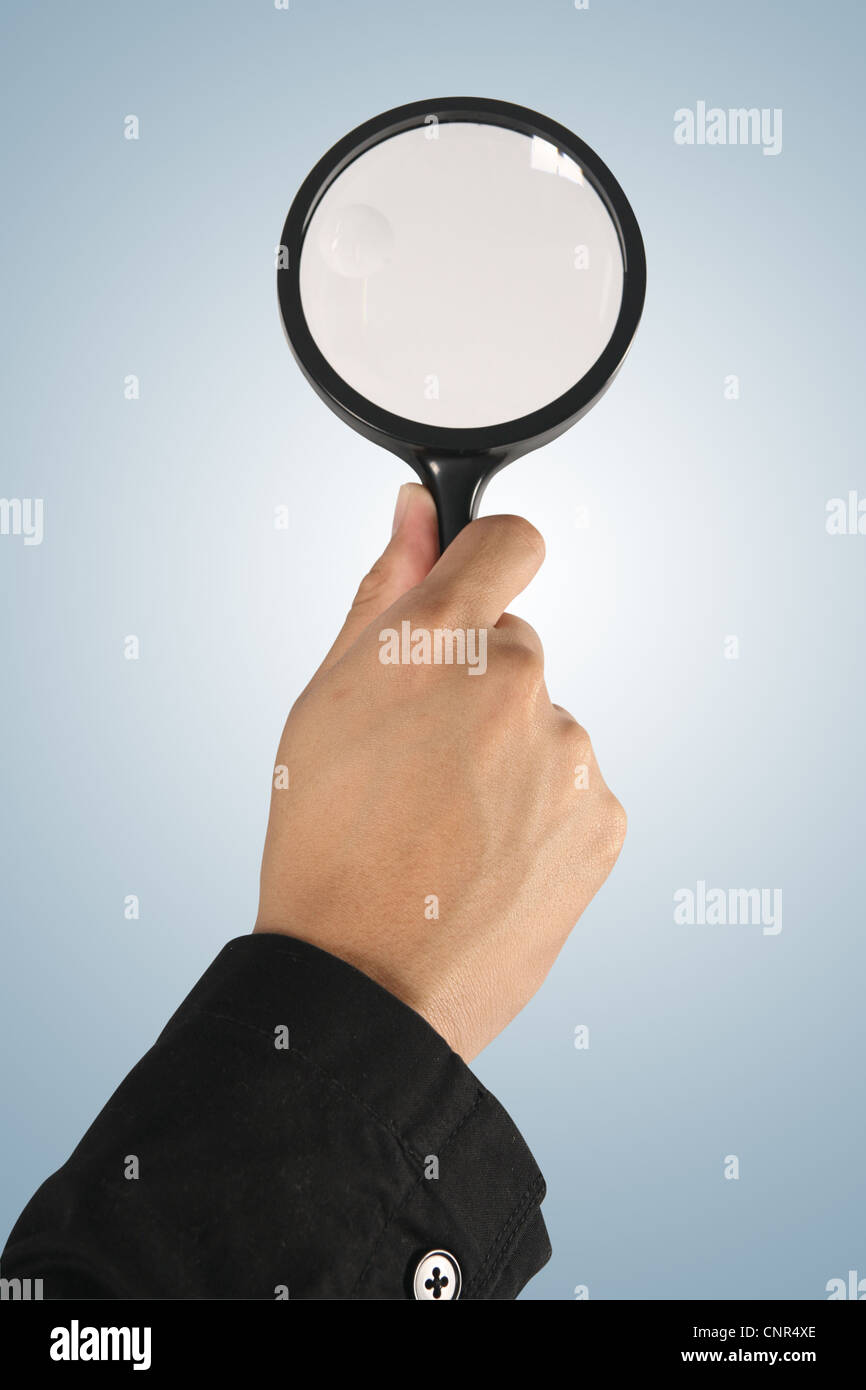 Magnifying glass in hand on blue background (path in side) Stock Photo